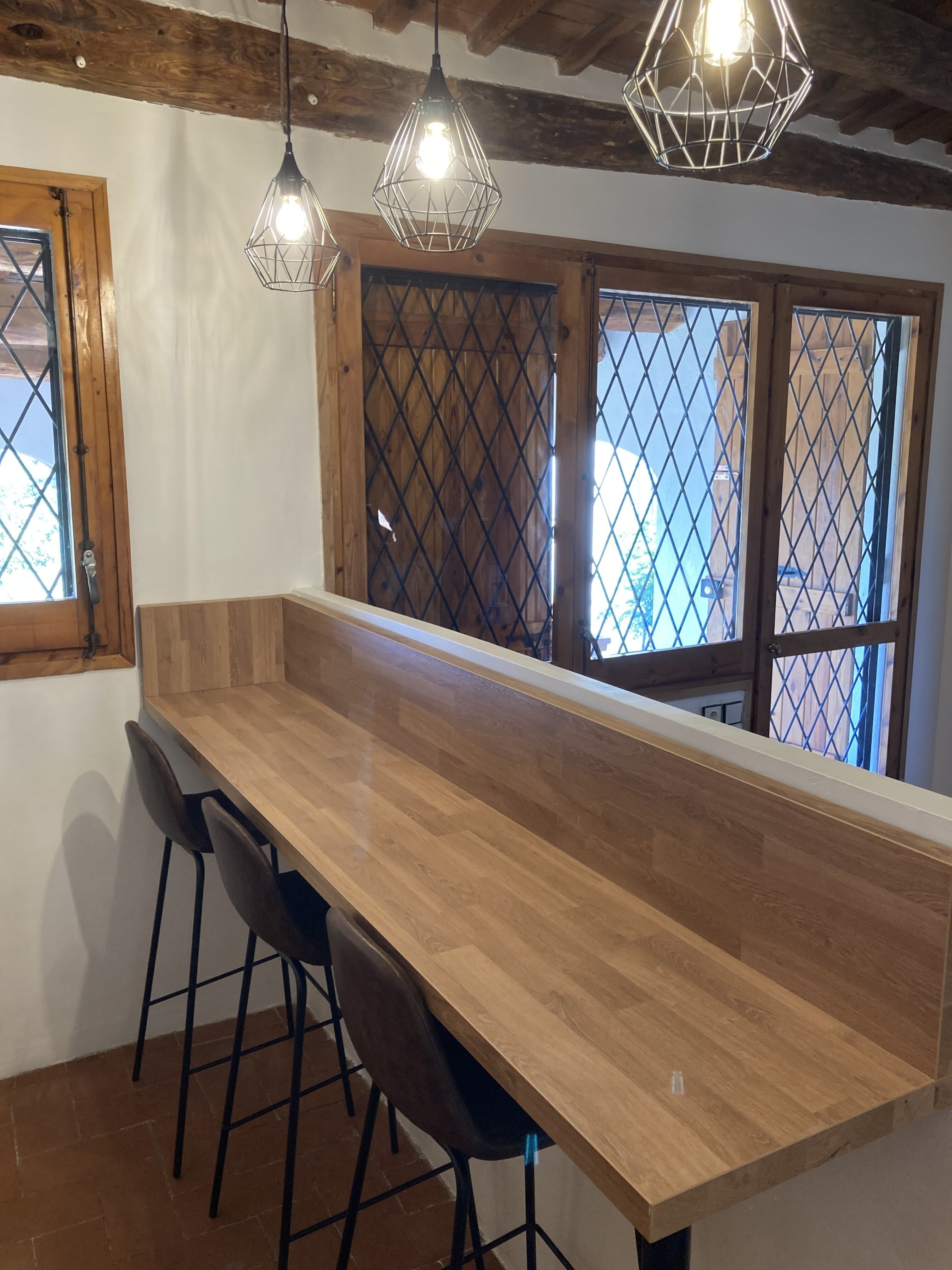 Taulell de fusta amb tamborets al costat de la finestra de l’Habitació Suite