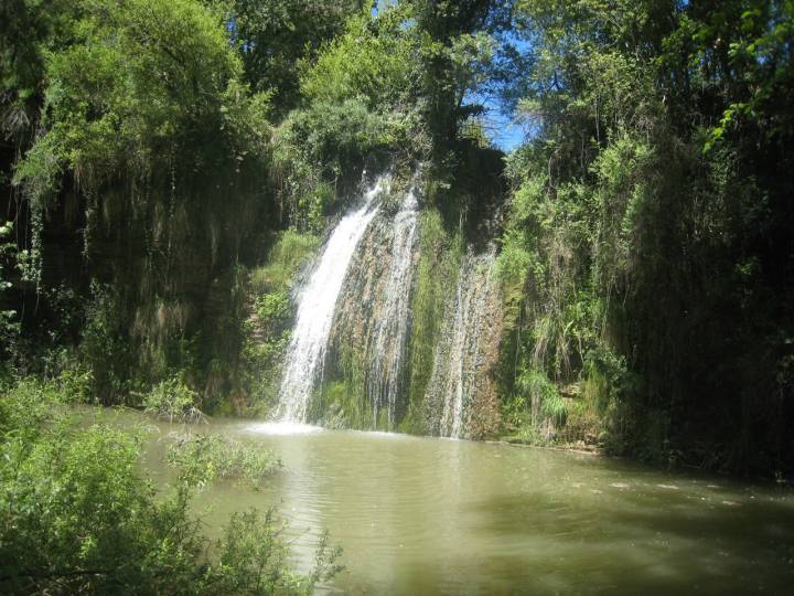 Els Pobles de Pedra que Has de Visitar 2 Cascada del Gorg del Nafre en Copons, Cataluña, rodeada de exuberante vegetación y un cuerpo de agua en la base