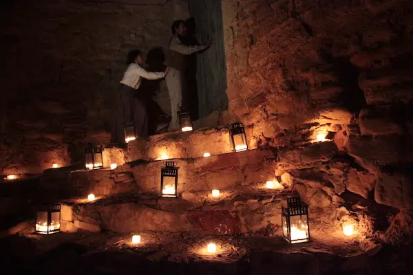 Els Pobles de Pedra que Has de Visitar 3 Dos personas explorando un antiguo edificio iluminado por linternas durante la Apagada de Misteri en el Festival de Leyendas de Cataluña en Sant Martí de Tous